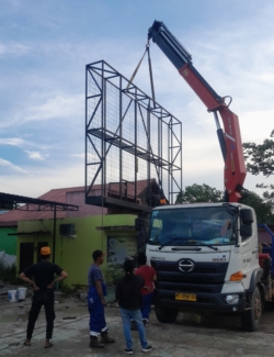 Proses ereksi rangka videotron outdoor menggunakan crane di lokasi proyek